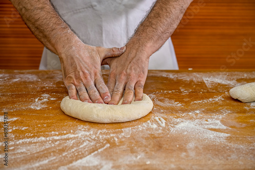 Baker kneading artisan bread in the bakery.