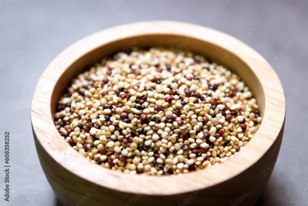Pile of mixed raw quinoa (Three colors) in wooden bowl on grey background. Quinoa provides protein, dietary fiber, B vitamins, and dietary minerals in rich. Super food of life. Pile of mixed raw quinoa (Three colors) in wooden bowl on grey background. Quinoa provides protein, dietary fiber, B vitamins, and dietary minerals in rich. Super food of life.