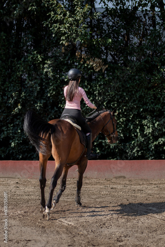 Vertical shot of a young woman riding a horse taking riding lessons