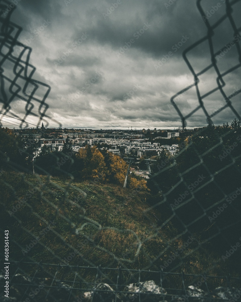 A gloomy view of the metropolis through a torn mesh fence: the concept of freedom