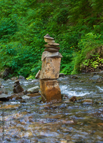 Composition of many river stones among the greenery on a sunny summer day. Selective focus.