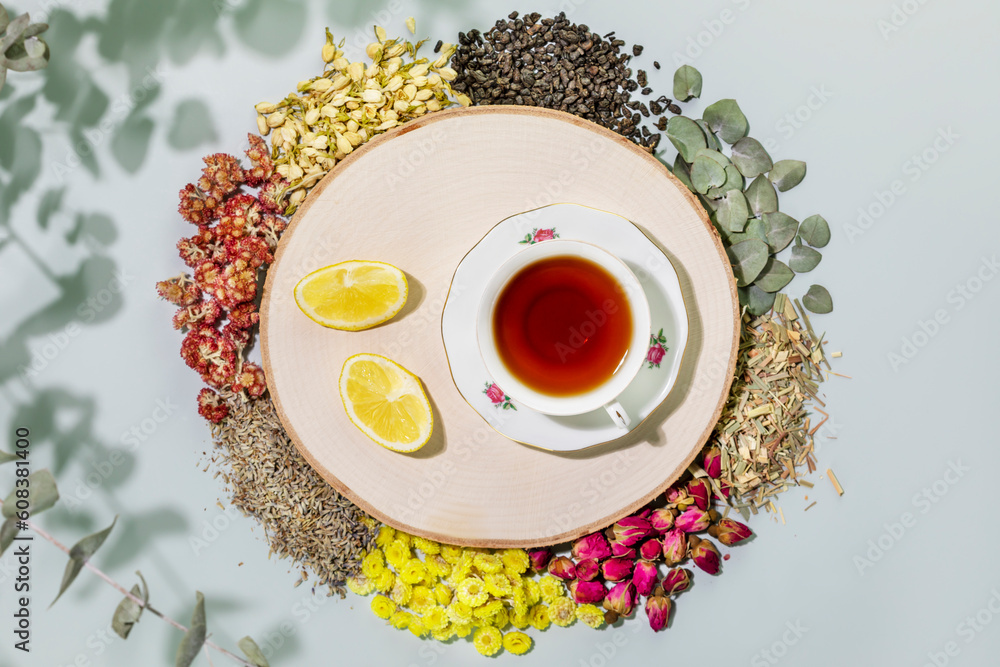 Organic herbal tea. Still life with healing herbal tea, healthy drink and home herbal apothecary. Dry wild growing flowers and herbs, cup of tea and lemon slices on blue background. Flat lay Organic herbal tea. Still life with healing herbal tea, healthy drink and home herbal apothecary. Dry wild growing flowers and herbs, cup of tea and lemon slices on blue background. Flat lay