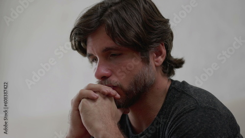 One preoccupied young man thinking deeply about life problematic issues. Worried male person in 30s with hand in chin with thoughtful expression