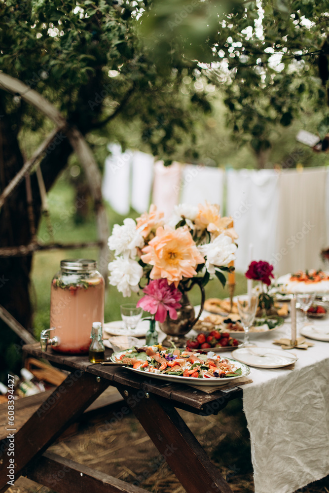 decorated wooden picnic table in an apple orchard. prepared place for outdoor party. table setting with snacks and drinks for the company. decorated wooden picnic table in an apple orchard. prepared place for outdoor party. table setting with snacks and drinks for the company.