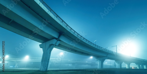 Road overpass. Panorama with bridge in evening. Modern overpass bottom view. Road transport infrastructure of city. Road junction under night sky. Overpass on giant columns. Sunset over bridge.