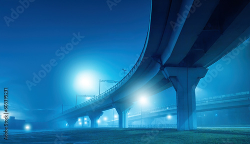 Bridge for cars or trains. Major road junction. Overpass on supports at night. Transport infrastructure of city. Road architecture. Overpass on concrete supports. Road bridge over river