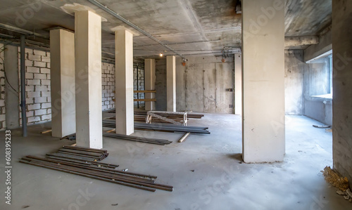 Building under construction. Property renovation. Room with concrete pillars. Thin pipes are located on floor. Process of building enterprise. House under construction view from inside.