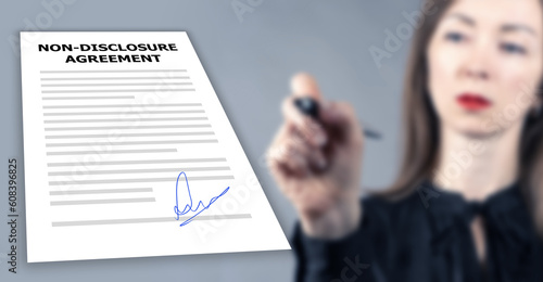 Non-disclosure agreement. NDA agreement. Businesswoman signs document. Paper with NDA rules. Non disclosure agreement logo on contract. NDA to protect company data. Selective focus. photo