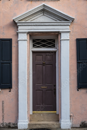 A colonial style front door with an eccentric door frame in sunlight.