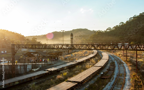 Trens e trilhos na cidade de Paranapiacaba, Santo André, Brasil, durante o pôr-do-sol. Torre do relógio marcando o horário de partidas em meio aos vagões.