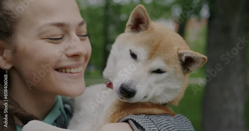 Close-up portrait of loving woman kissing cute shiba inu dog expressing love and happinness outdoors on summer day. Animal and affectionate human concept. photo
