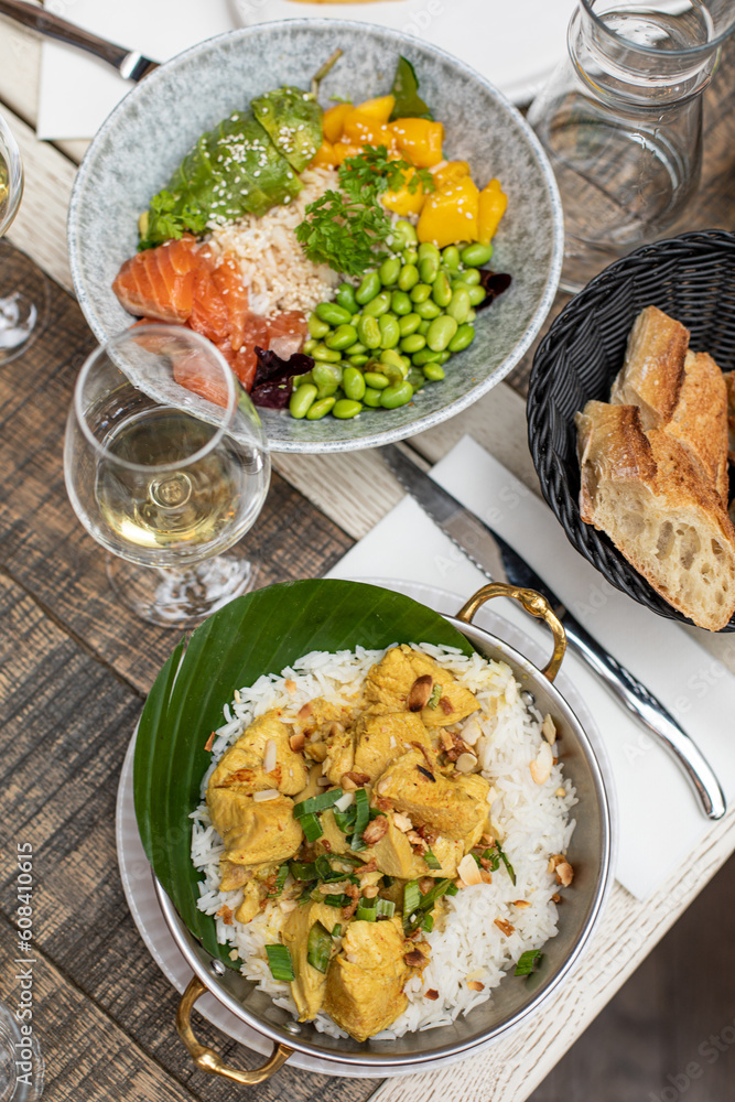 Different dishes, wine in glass lying on table of Parisian cafe. Meat, rice, bread and vegetables arranged on plates. Different dishes, wine in glass lying on table of Parisian cafe. Meat, rice, bread and vegetables arranged on plates.
