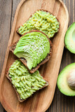 Board of tasty avocado toasts on wooden background