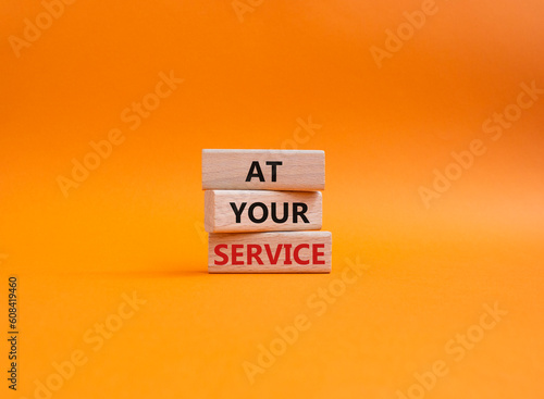 At your service symbol. Wooden blocks with words At your service. Beautiful orange background. Business and At your service concept. Copy space.