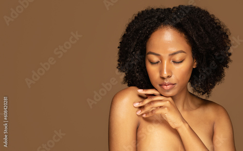 Young half-naked black woman touching her shoulder, copy space