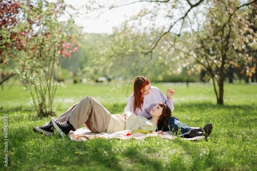 Obraz na plátně Beautiful two ladies lesbian laying down on the grass in the middle of the park