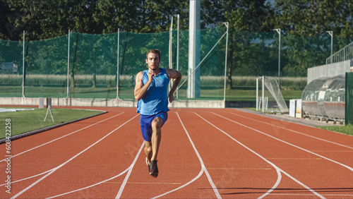 Caucasian male athlete in blue sportswear running alone along an athletic track on the stadium © 24K-Production