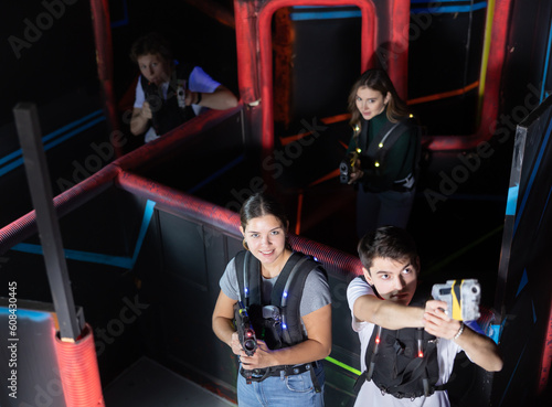 Laser tag players cheerful positive smiling guys and girls playing in teams in dark laser tag room. View from above © JackF
