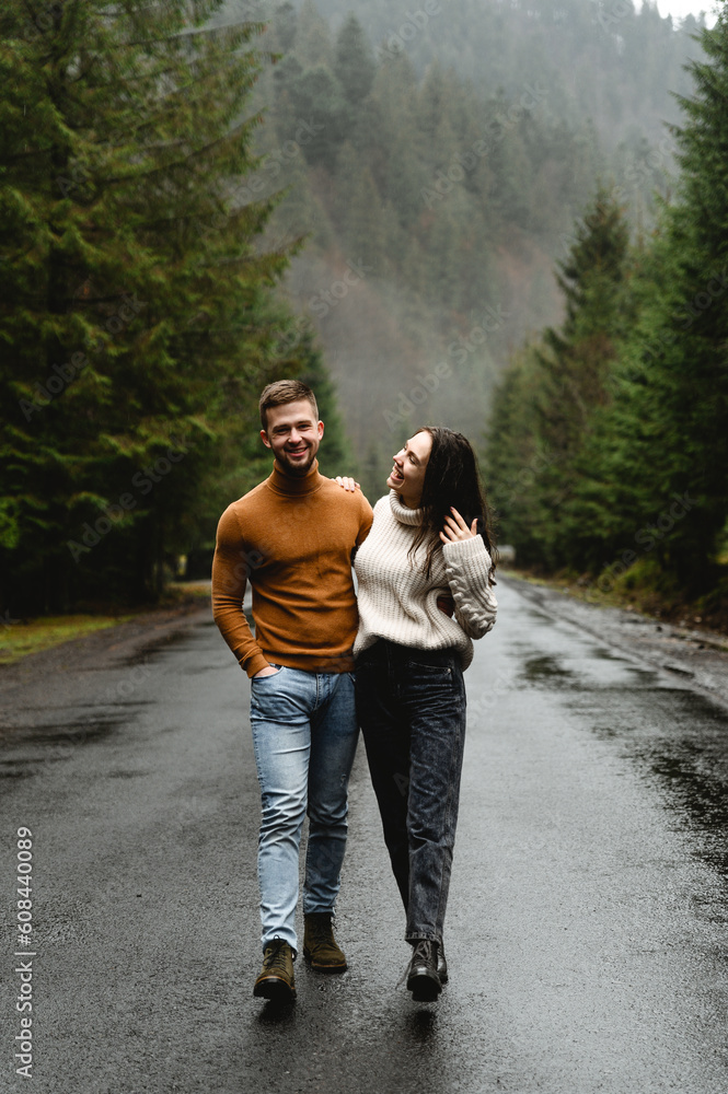 lovers laugh and embrace walking on a wet road in a mountainous area. autumn walk of a guy with a girl. joint trip lovers laugh and embrace walking on a wet road in a mountainous area. autumn walk of a guy with a girl. joint trip