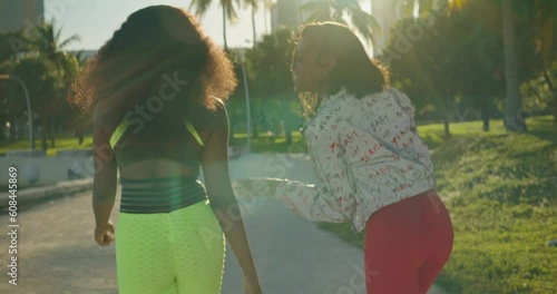 Two African American young women having fun while walking at a park