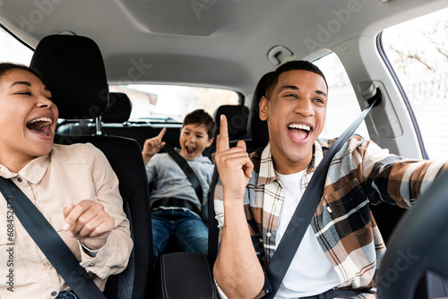 Excited young african american family singing riding new car and having fun enjoying summer road trip on vacation