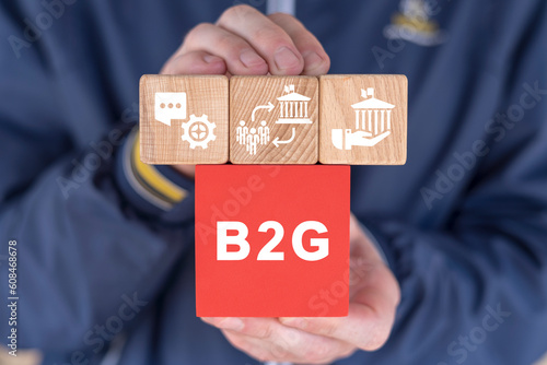 Man holding colorful blocks with icons and abbreviation: B2G. Concept of B2G - Business To Government. Business governance marketing organization process. photo
