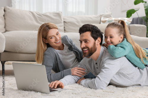 Happy family with laptop on floor at home