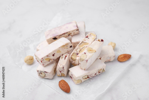 Pieces of delicious nutty nougat on white table