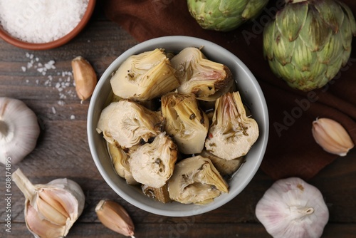 Pickled and fresh artichokes on wooden table, flat lay