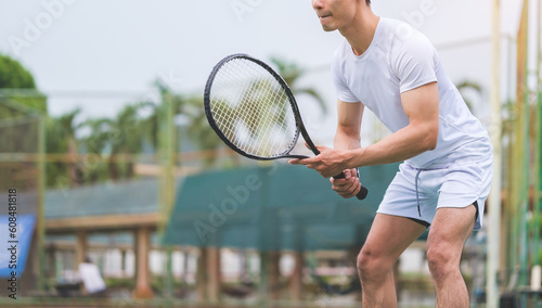 Young male tennis player holding a racket and standing in a ready position. © wattana