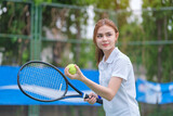 Young female tennis player with racket and ball preparing to serve at beginning of game or match.