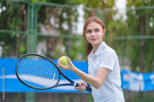 Young female tennis player with racket and ball preparing to serve at beginning of game or match.