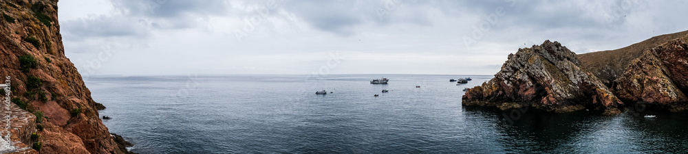Panoramic view of the coast of the Berlenga Islands in the Atlantic Ocean of Portugal. Cloudy landscape of the Iberian Peninsula. Fishing boats in the water. Panoramic view of the coast of the Berlenga Islands in the Atlantic Ocean of Portugal. Cloudy landscape of the Iberian Peninsula. Fishing boats in the water.