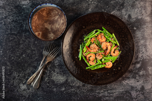 Healthy food stir fried shrimp asparagus teriyaki in plate on black slate table.