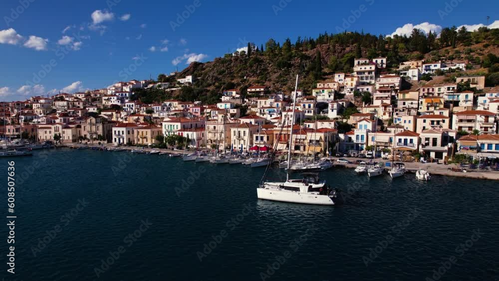 Drone view of Yacht sailing past coastal town in Greece on a sunny day Drone view of Yacht sailing past coastal town in Greece on a sunny day