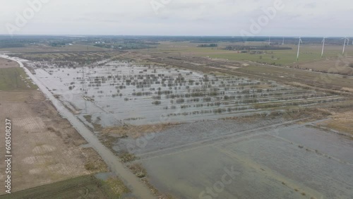 Aerial establishing view of high water in springtime, Alande river (Latvia) flood, brown and muddy water, agricultural fields under the water, sunny day, wide drone panorama shot moving right photo