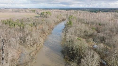 Aerial establishing view of high water in springtime, Barta river (Latvia) flood, brown and muddy water, sunny day, ascending drone shot photo