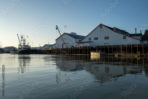Obraz na plátně Fishing Cannery Industry along the harbor with reflection showing in the water w