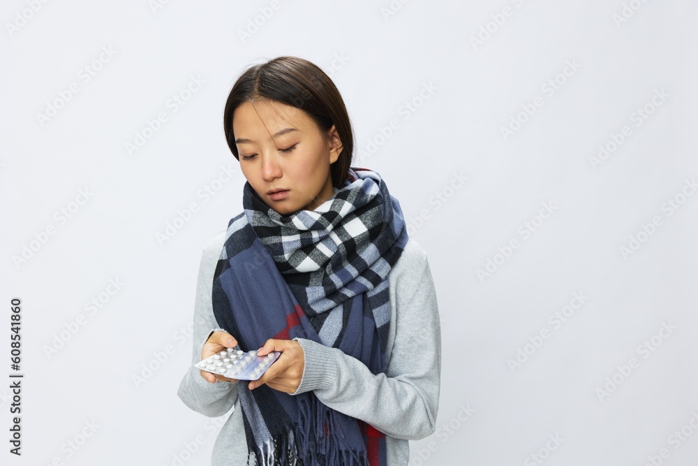 Asian woman headache cold flu holding medicine and pills with fever is sick from the virus on a white background, copy space