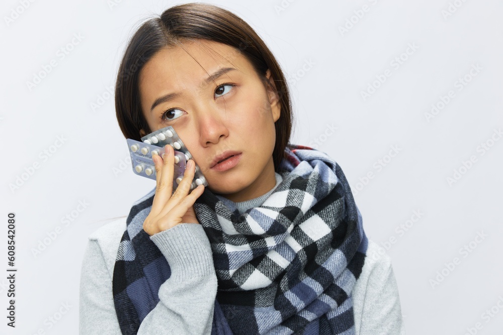Asian woman headache cold flu holding medicine and pills in checkered plaid with fever sick of virus on white background, copy space Asian woman headache cold flu holding medicine and pills in checkered plaid with fever sick of virus on white background, copy space