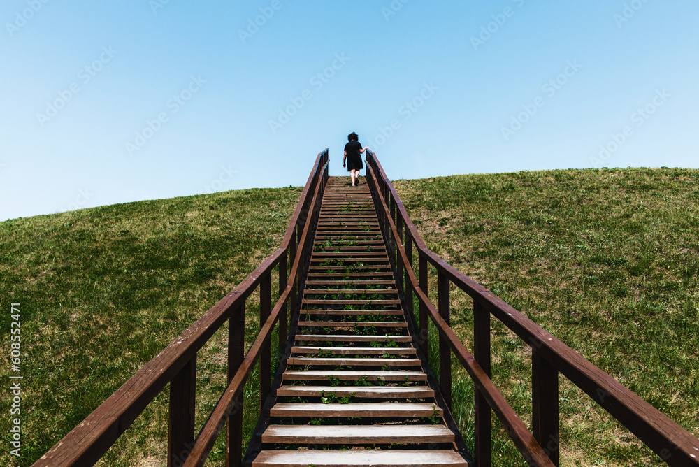 Stairs to heaven. Stairs into the future.Woman climbing wooden stairs at mountain.