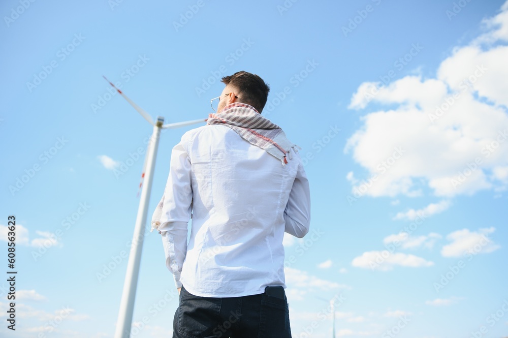 Arab man standing with wind turbine on mountain Arab man standing with wind turbine on mountain