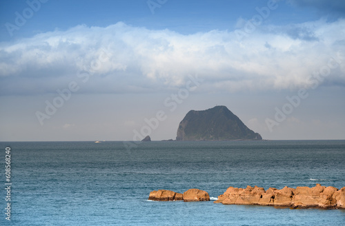 Fast moving clouds over the island. The boat sails on the blue sea. View of Keelung Island from Wanli Beach in New Taipei City. Taiwan. photo