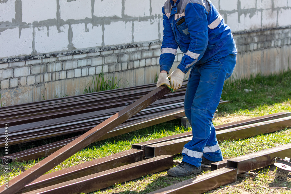 A worker in blue overalls works with metal pipes at a construction site A worker in blue overalls works with metal pipes at a construction site