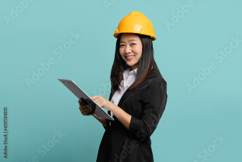 Young female engineer using a clipboard isolated on green background