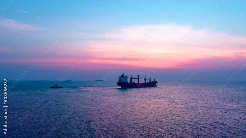 Seascape and silhouette container ship floating in sea and over the sunlight background