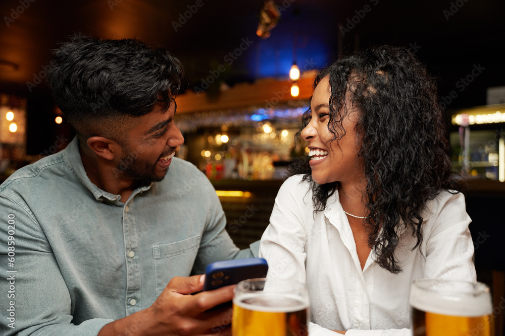 Young multiracial couple in casual clothing smiling face to face with mobile phone at bar Young multiracial couple in casual clothing smiling face to face with mobile phone at bar