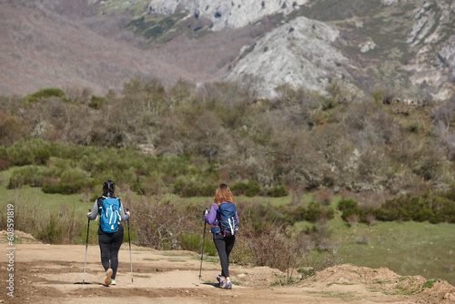 Two female backpacker hikers on a pathway. Mountain trekking. Copyspace
