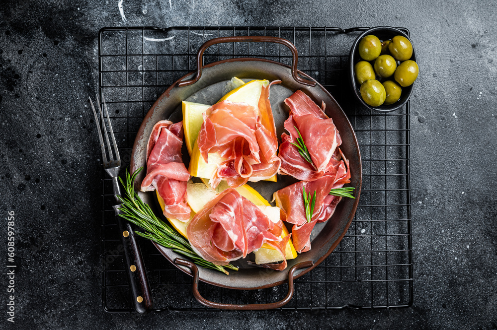 Italian prosciutto parma with melon and fresh rosemary. Black background. Top view