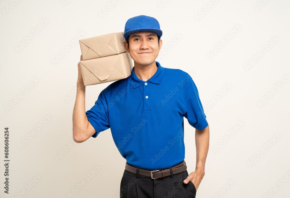Happy delivery asian man in blue uniform standing holding box parcel cardboard on isolated white background. Smiling male service worker. Delivery courier and shipping service. Happy delivery asian man in blue uniform standing holding box parcel cardboard on isolated white background. Smiling male service worker. Delivery courier and shipping service.